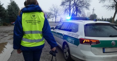 Inspektor Ochrony Środowiska stojący w punkcie kontrolnym na tle samochodu Służby Celno-Skarbowej