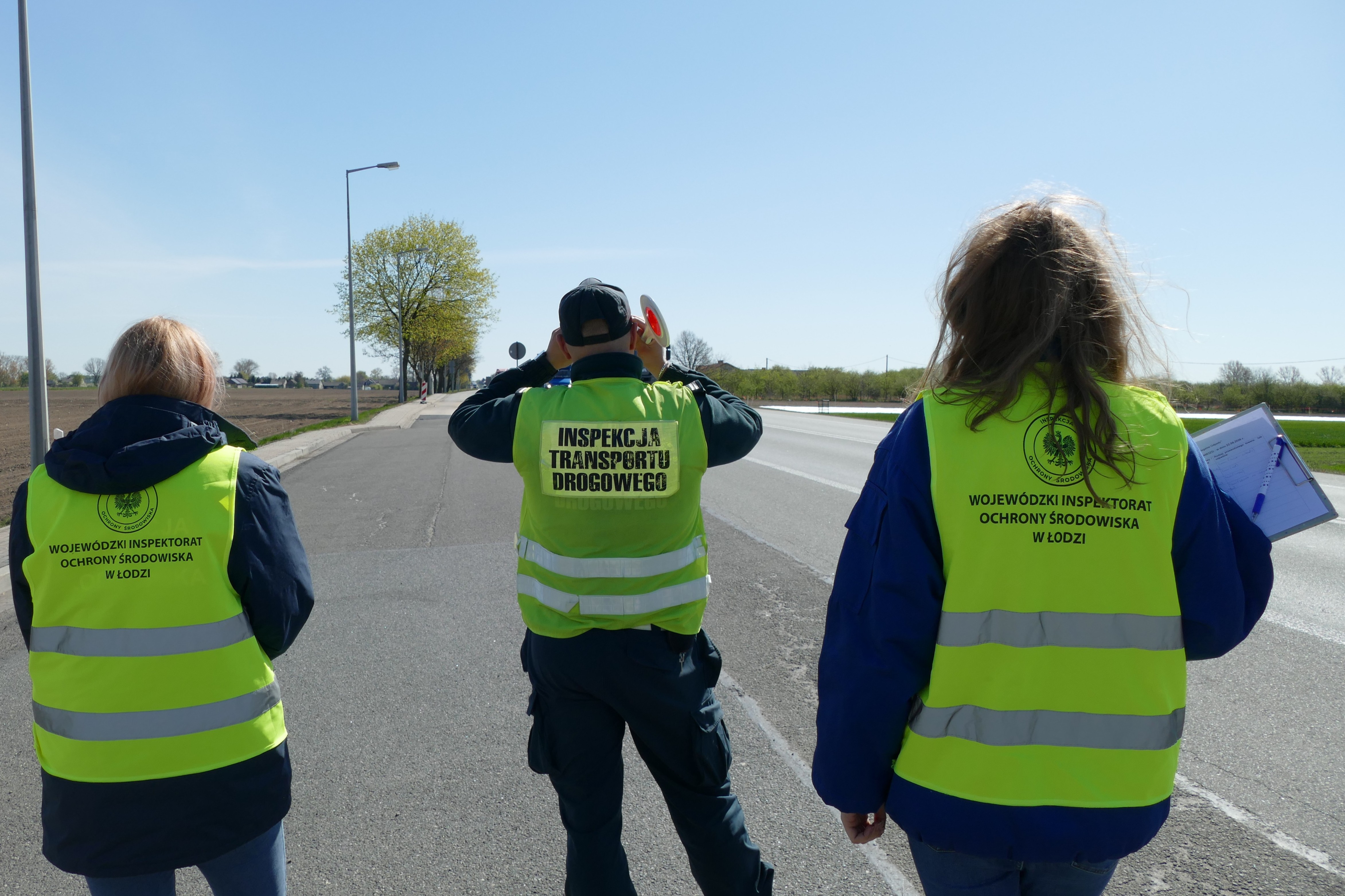 Pracownicy WIOŚ i pracownik Inspekcji Transportu Drogowego stojący na drodze